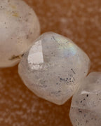 Detalle macro en primer plano de una cuenta facetada de Labradorita blanca