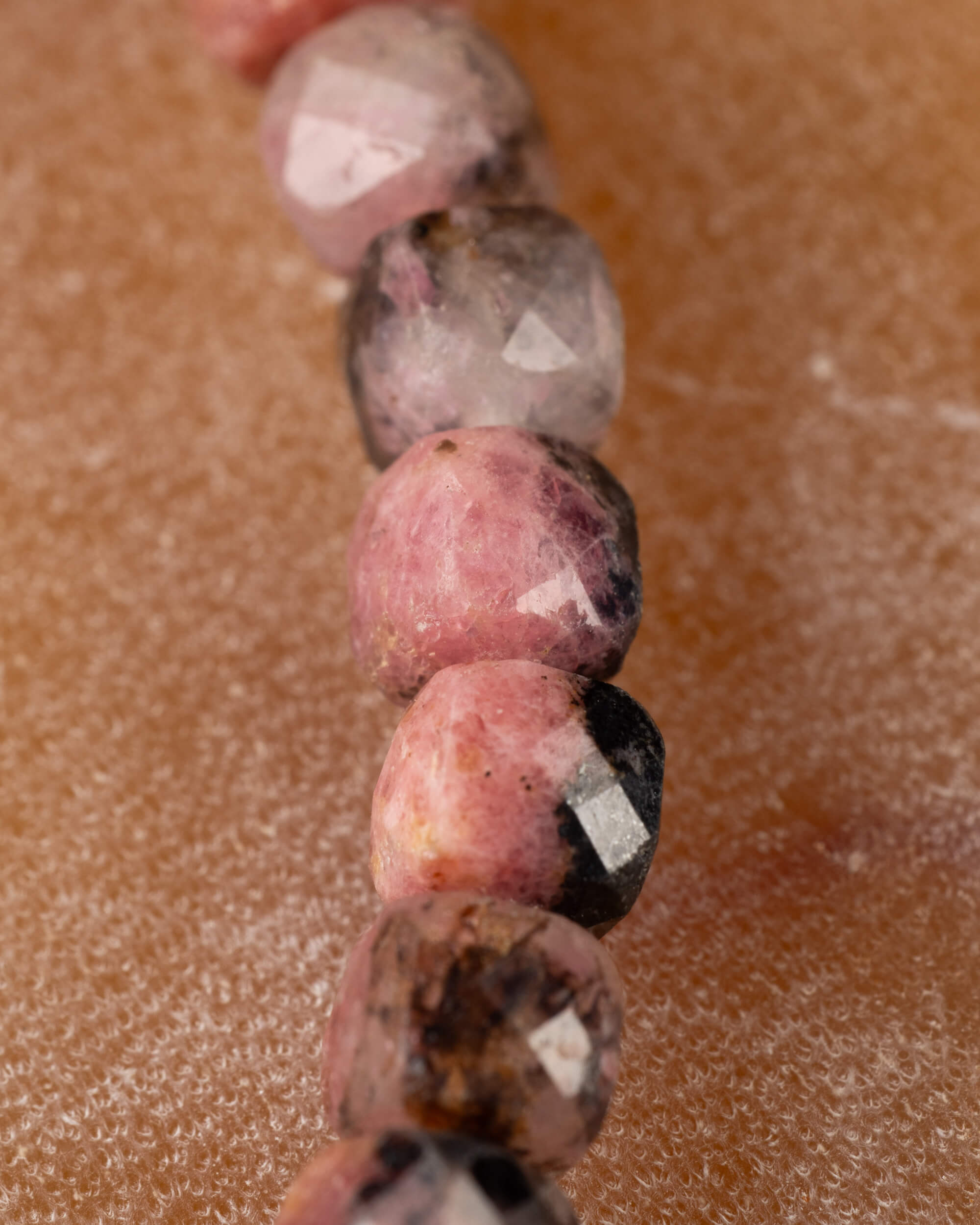 Detalle macro de cuentas facetadas de Rodonita en tonos rosa y gris