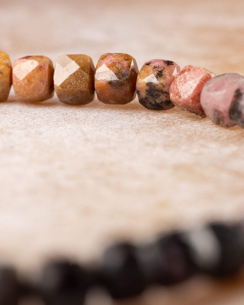 Pulsera de Rodonita en perspectiva, cuentas doradas y rosadas al frente