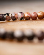 Pulsera de Rodonita en perspectiva, cuentas rosa y doradas al frente