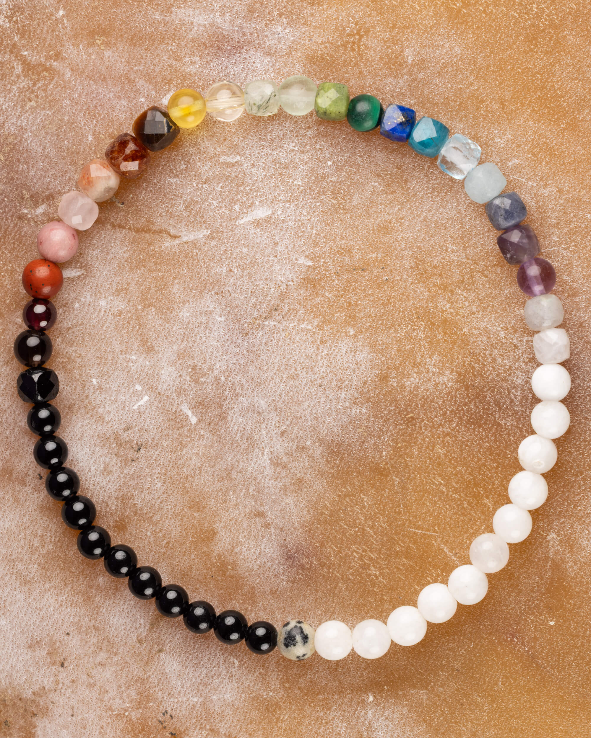 Pulsera Unidad de 4 mm con 23 minerales en degradado de color, pieza completa sobre superficie de mármol