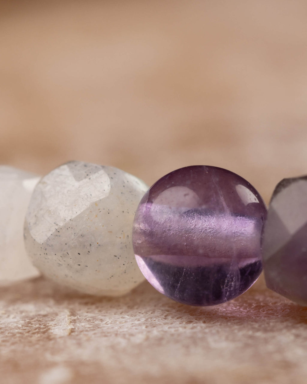 Detalle macro extremo de una cuenta esférica de Amatista entre Piedra Luna y Fluorita