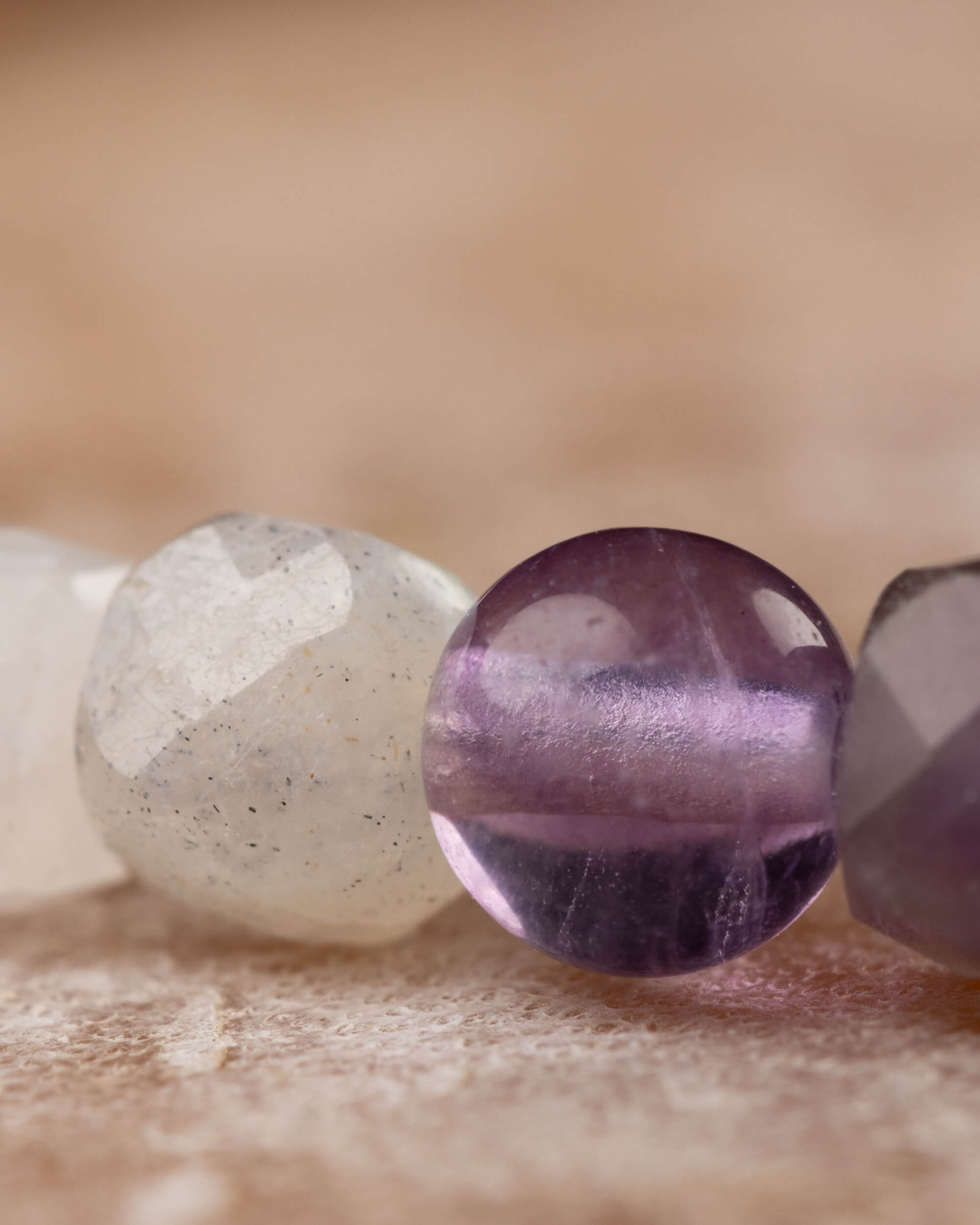 Detalle macro extremo de una cuenta esférica de Amatista entre Piedra Luna y Fluorita