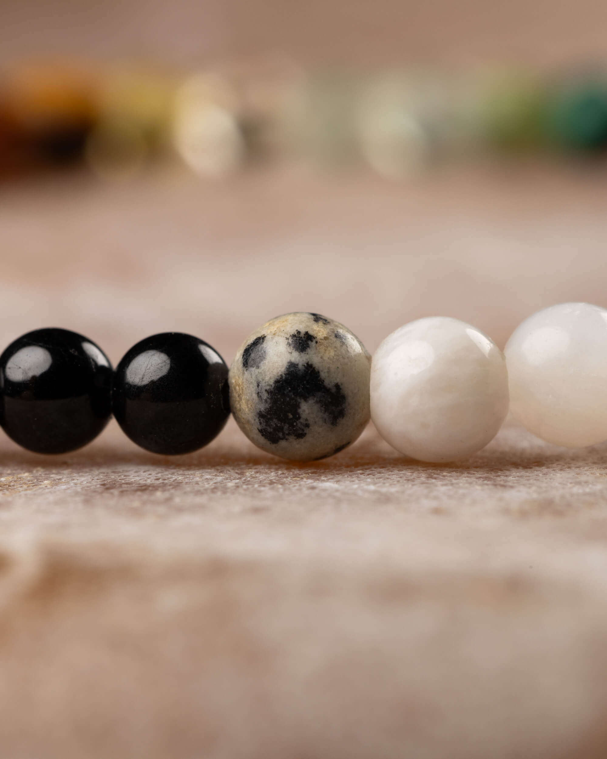 Detalle macro de las cuentas de Turmalina Negra, Jaspe Dálmata y Piedra Luna en la pulsera Unidad