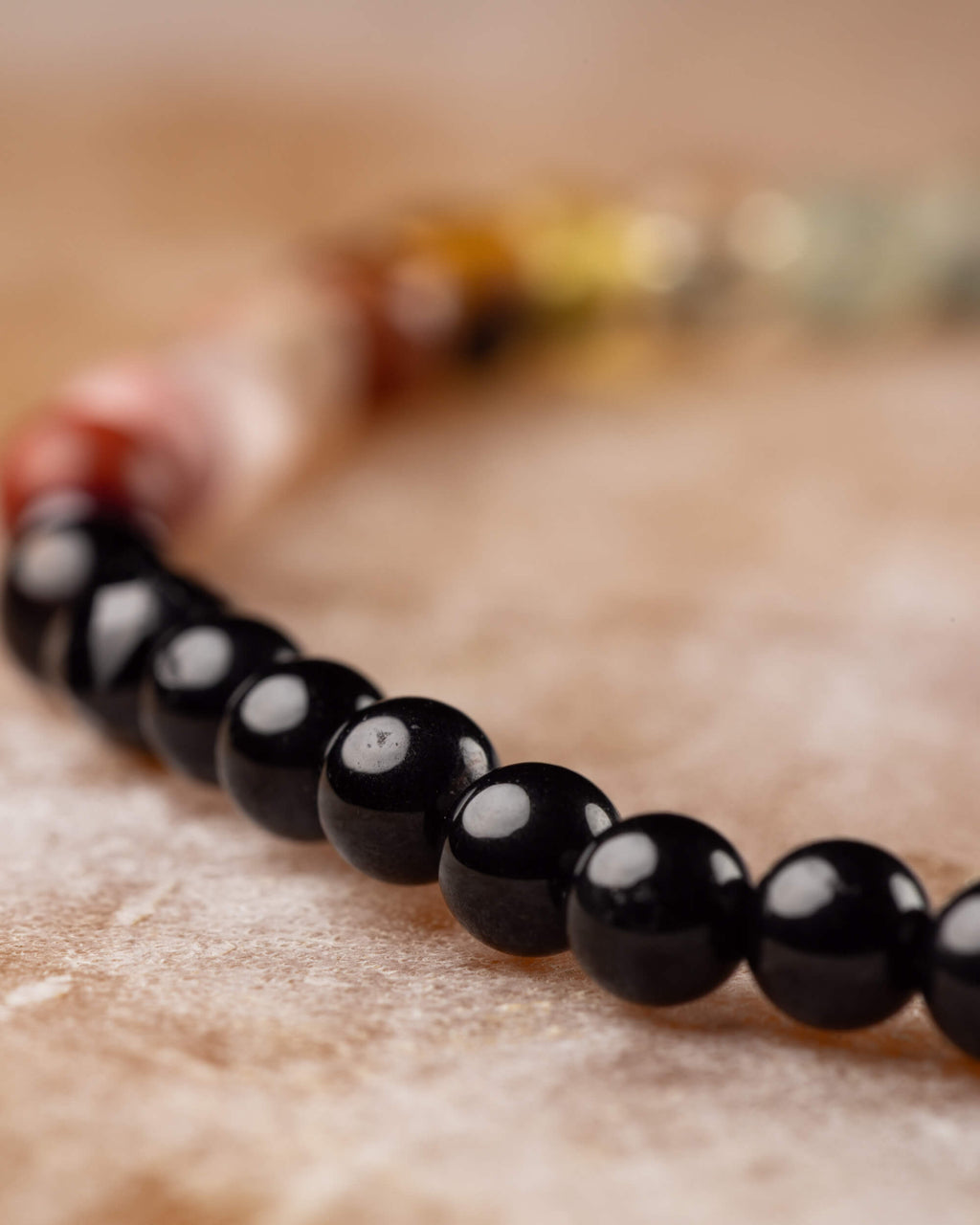 Detalle macro de las cuentas de Turmalina Negra con degradado de color al fondo, pulsera Unidad