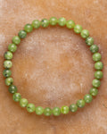 Pulsera de Jade Verde de 6 mm, pieza completa en forma circular sobre superficie de piedra