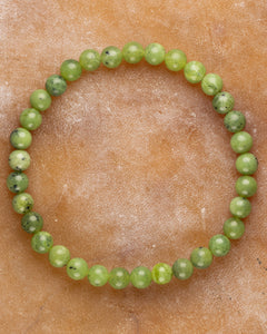 Pulsera de Jade Verde de 6 mm, pieza completa en forma circular sobre superficie de piedra
