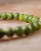 Pulsera de Jade Verde en perspectiva curva sobre superficie de piedra