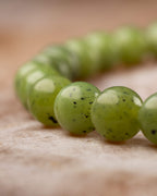 Detalle macro de las cuentas de Jade Verde con brillo y hilera al fondo