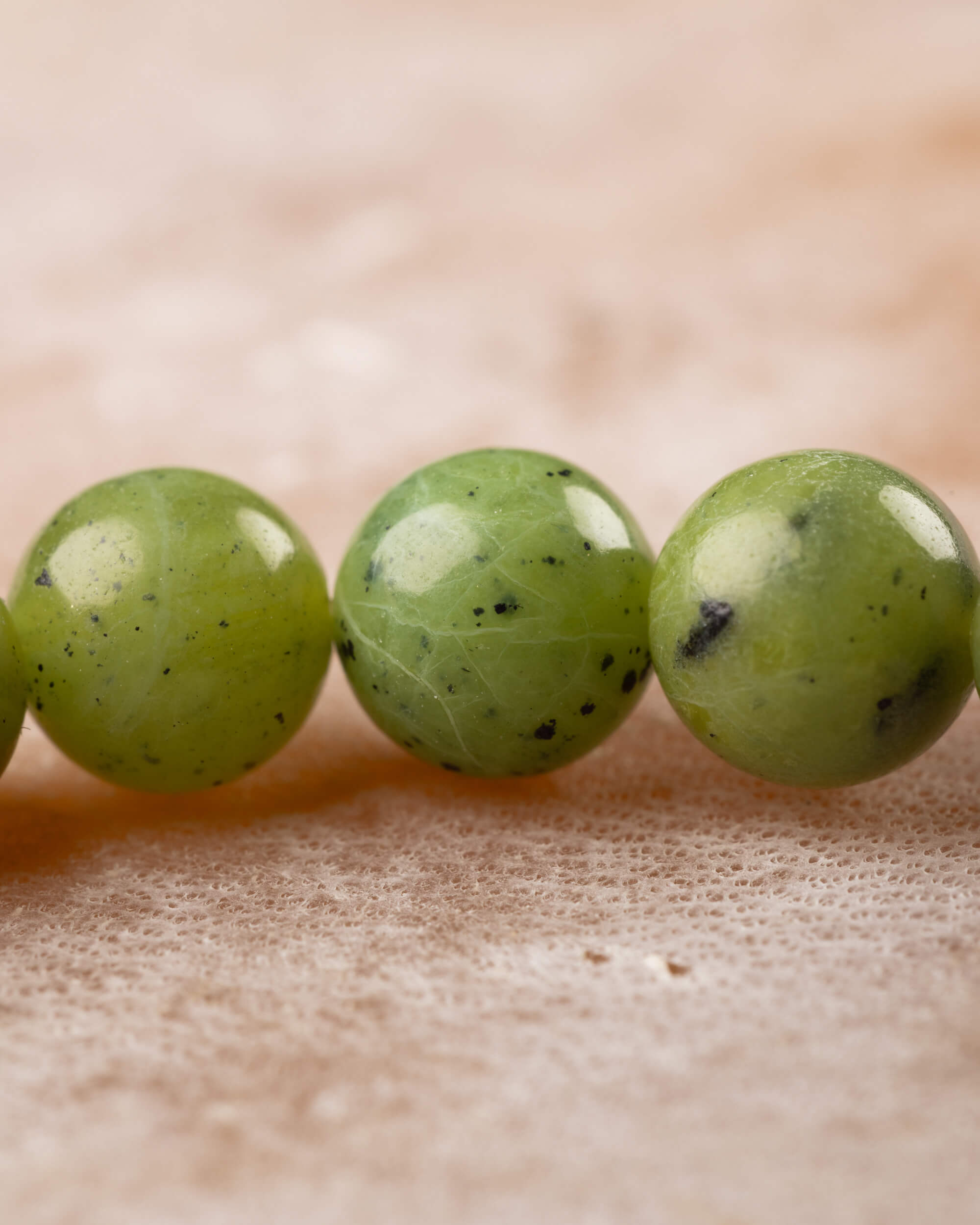 Detalle macro de las cuentas de Jade Verde con vetas y motas oscuras