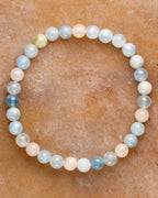 Pulsera de Berilos de 6 mm, pieza completa con tonos azul, rosa y crema sobre superficie ámbar