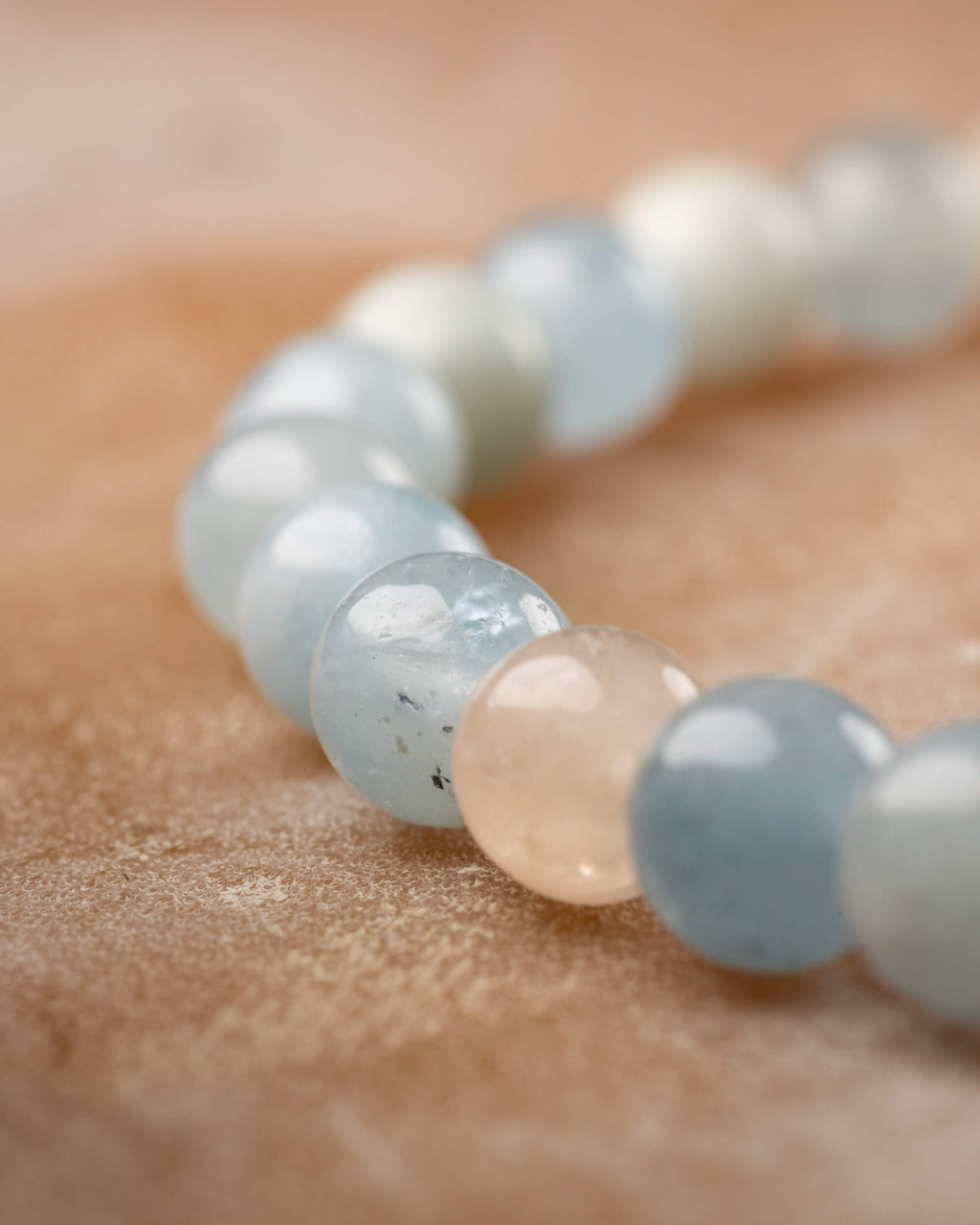 Detalle macro de cuentas de Berilos en fila, tonos crema, azul claro y aguamarina