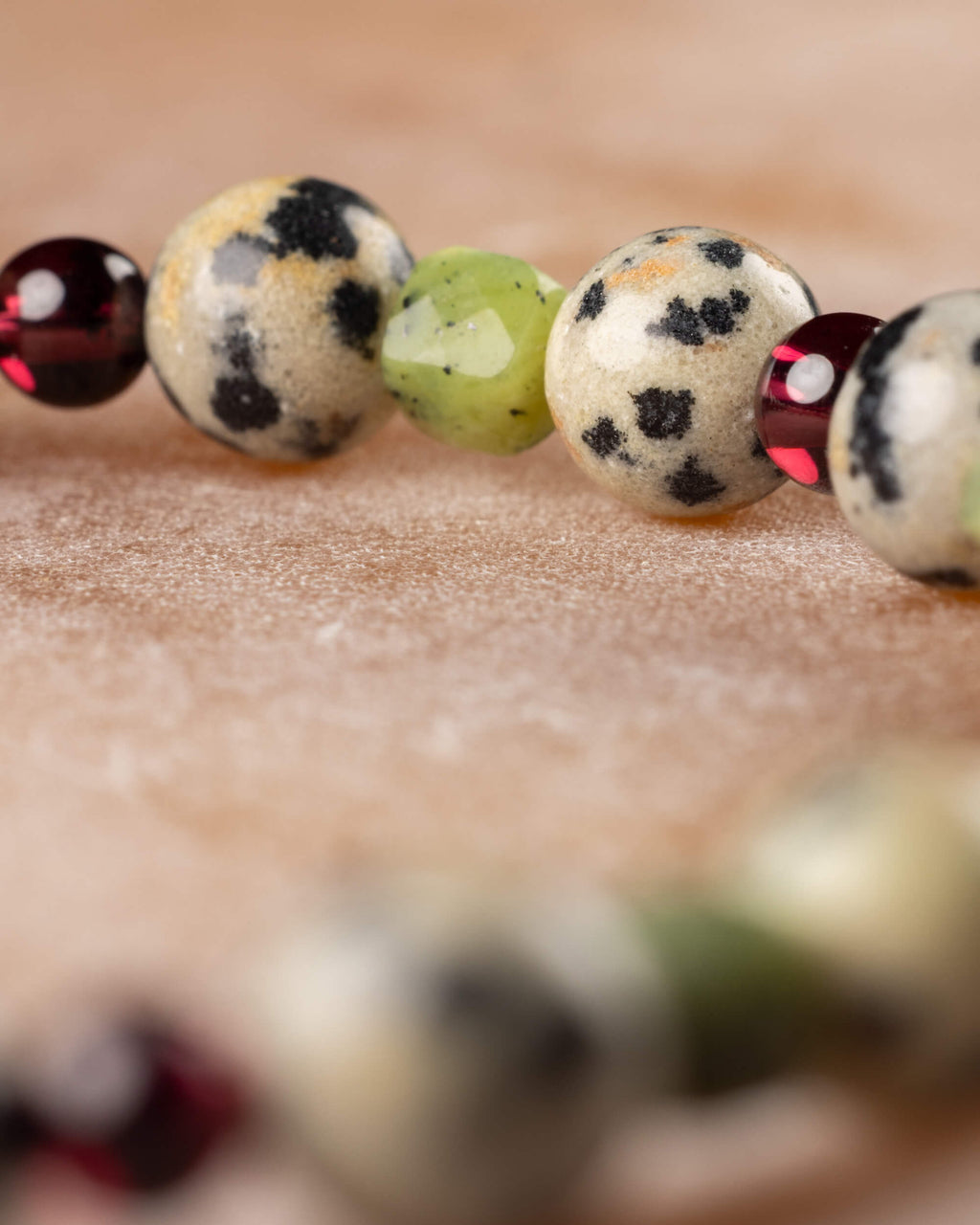 Detalle macro de las cuentas de Jaspe Dálmata, Jade Verde y Granate de la pulsera Guerrero Alegre