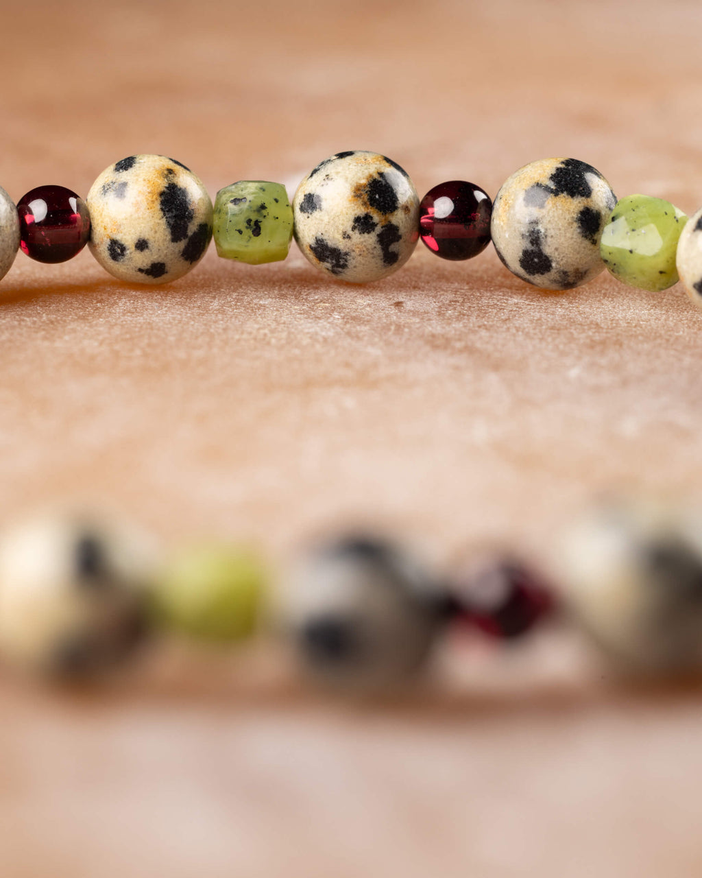 Detalle macro de las cuentas de Jaspe Dálmata, Jade Verde y Granate de la pulsera Guerrero Alegre