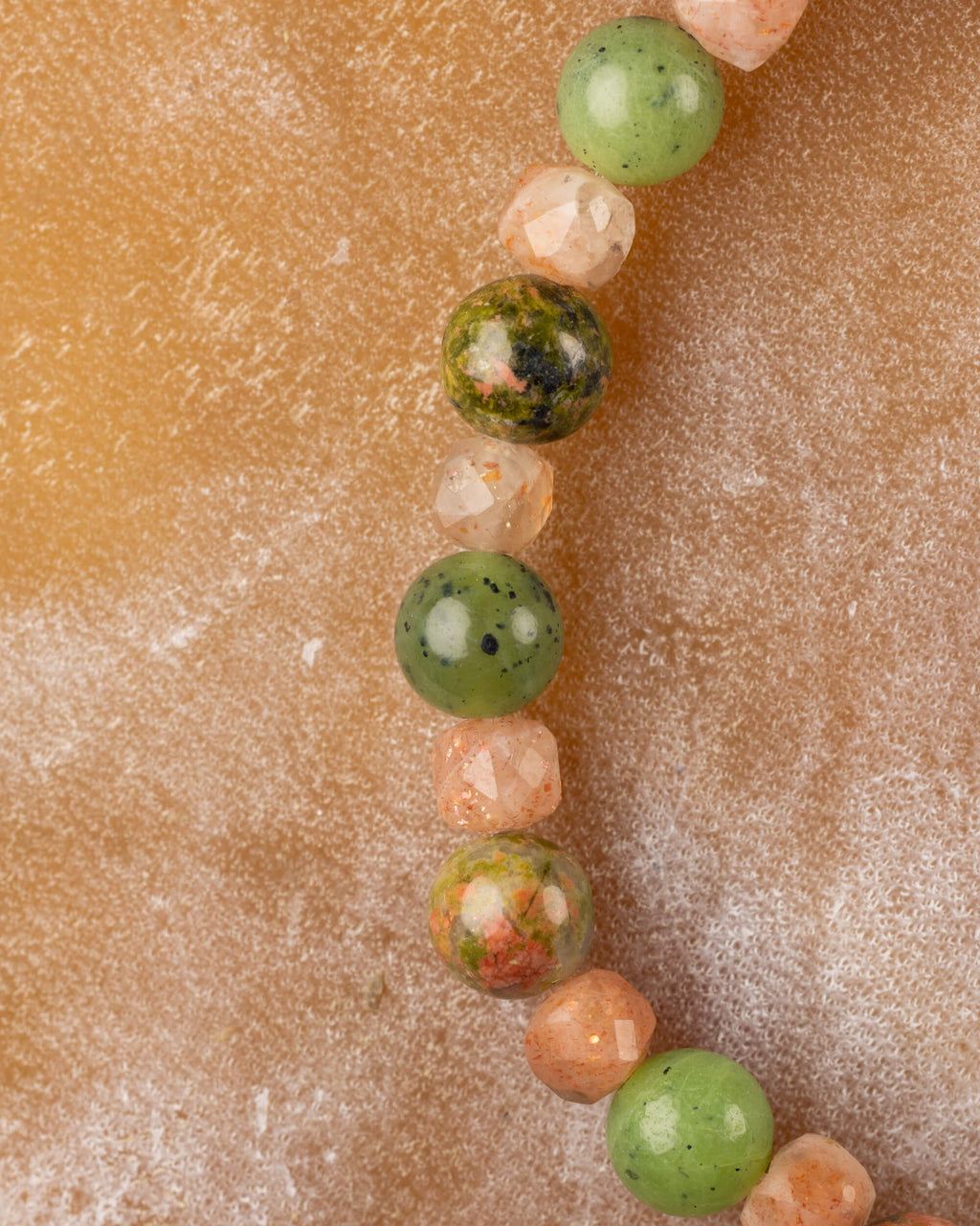 Cuentas de Piedra Sol y Jade Verde en curva, primer plano difuminado