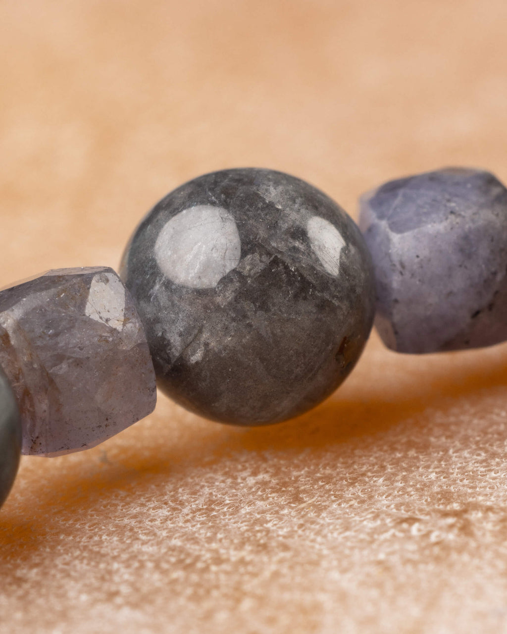 Cuenta redonda gris moteada junto a la faceta violeta grisacea, primer plano