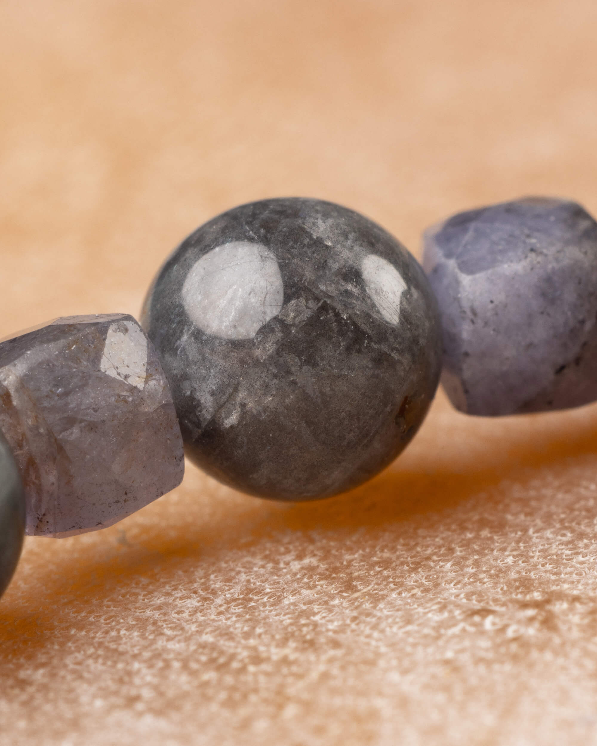 Cuenta redonda gris moteada junto a la faceta violeta grisacea, primer plano