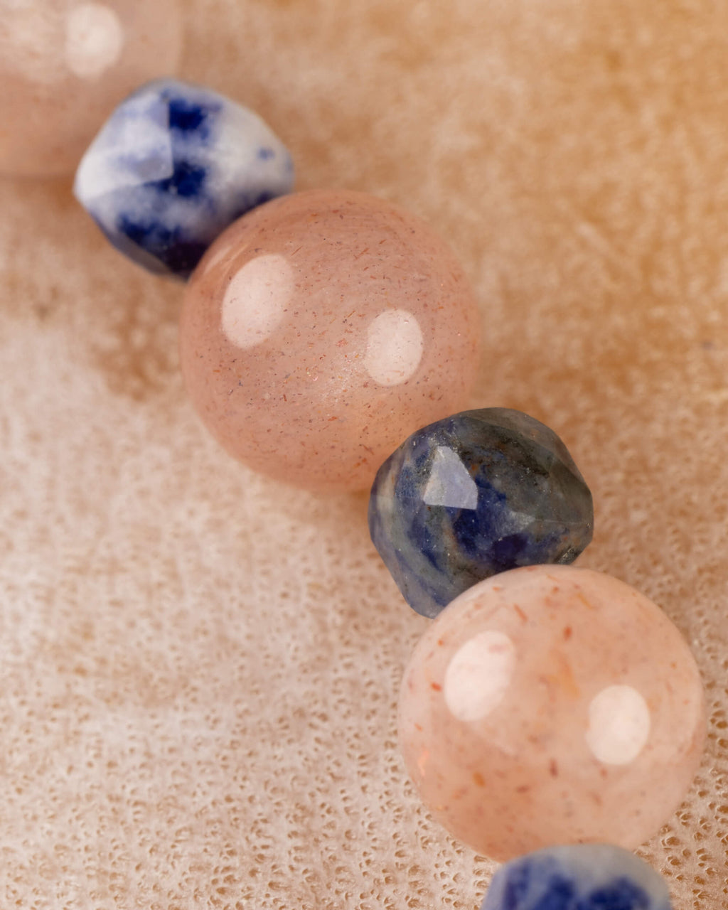 Cuentas de Piedra Sol y Sodalita en primer plano, curva descendente de la pulsera