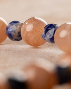 Cuentas de Piedra Sol y Sodalita en fila, enfoque en el centro de la pulsera