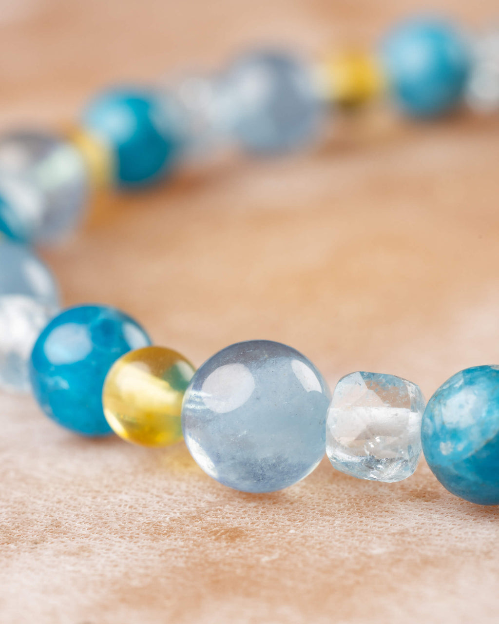 Detalle macro de las cuentas de Apatita Azul, Ámbar y Aguamarina en la pulsera