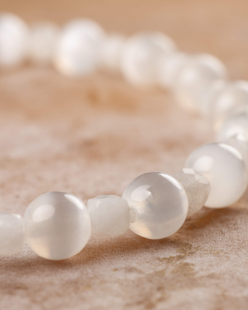 Pulsera de cuentas blancas de Selenita y Piedra Luna puesta en la muneca, brillo suave, sin relieve visible