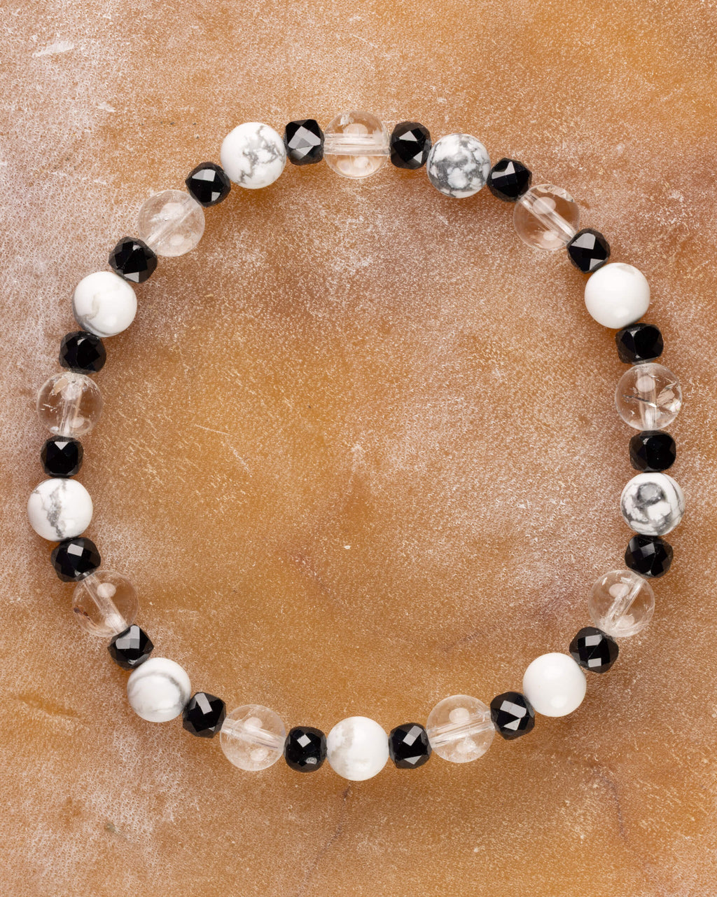 Pulsera de Espinela Negra, Howlita y Cuarzo Transparente, pieza completa sobre superficie de mármol claro