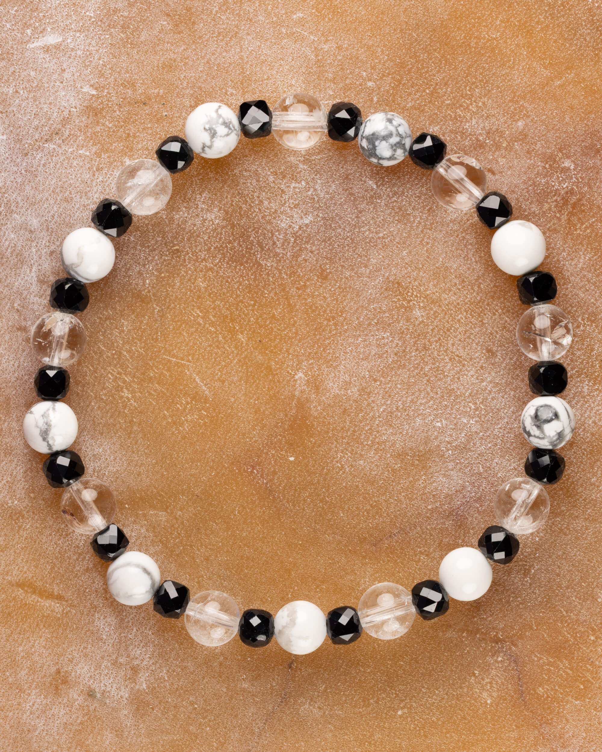 Pulsera de Espinela Negra, Howlita y Cuarzo Transparente, pieza completa sobre superficie de mármol claro