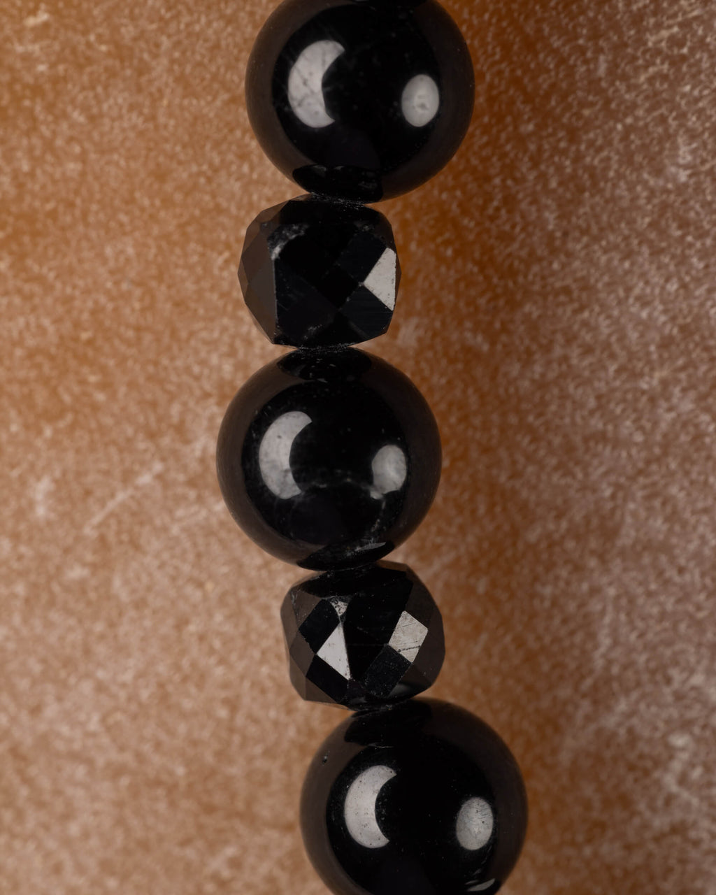 Detalle macro vertical de las esferas de Espinela Negra y las cuentas facetadas de Turmalina Negra