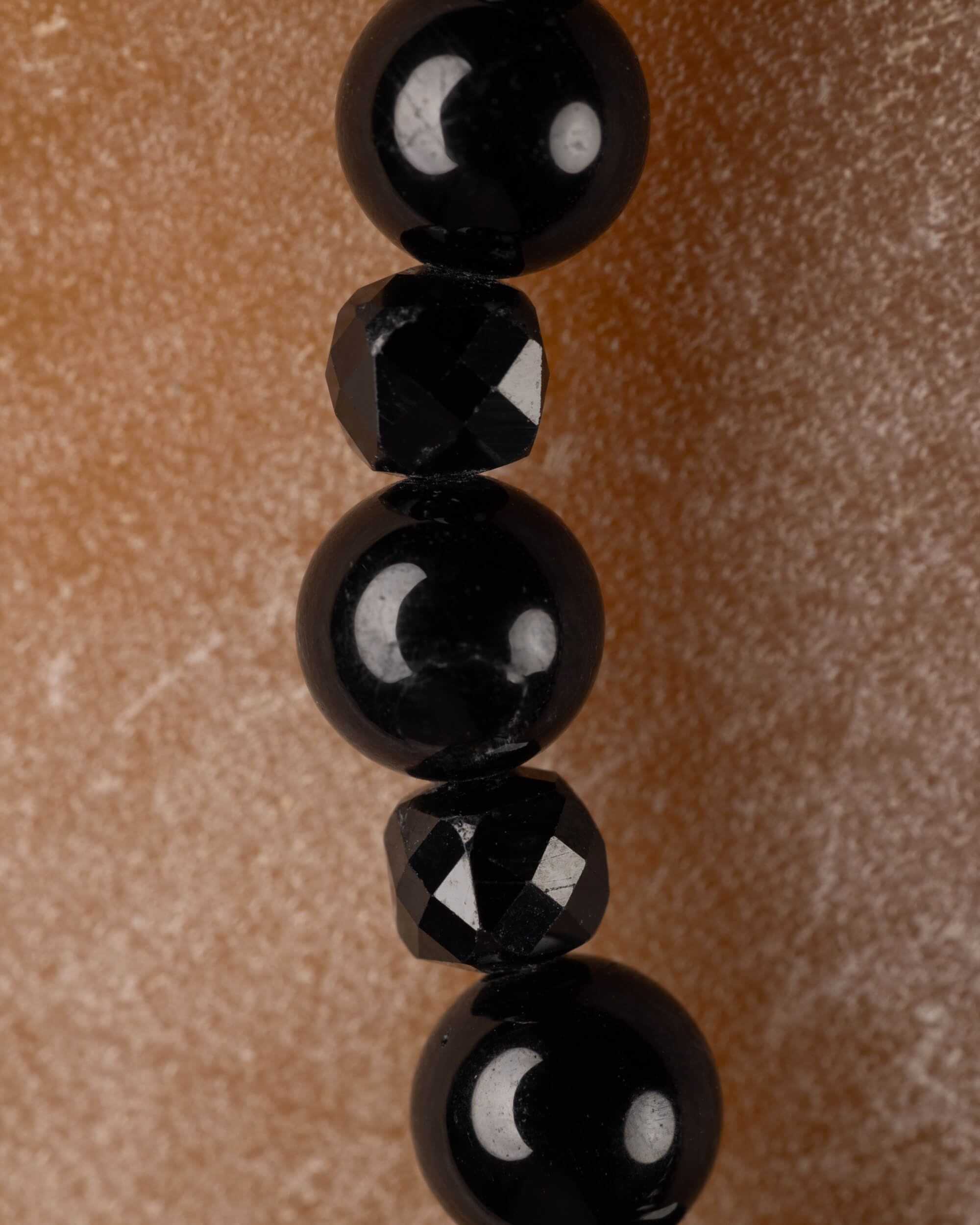 Detalle macro vertical de las esferas de Espinela Negra y las cuentas facetadas de Turmalina Negra
