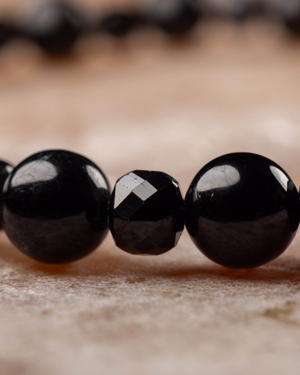 Detalle macro de las esferas de Espinela Negra y una cuenta facetada de Turmalina Negra