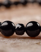 Detalle macro de las esferas de Espinela Negra y una cuenta facetada de Turmalina Negra