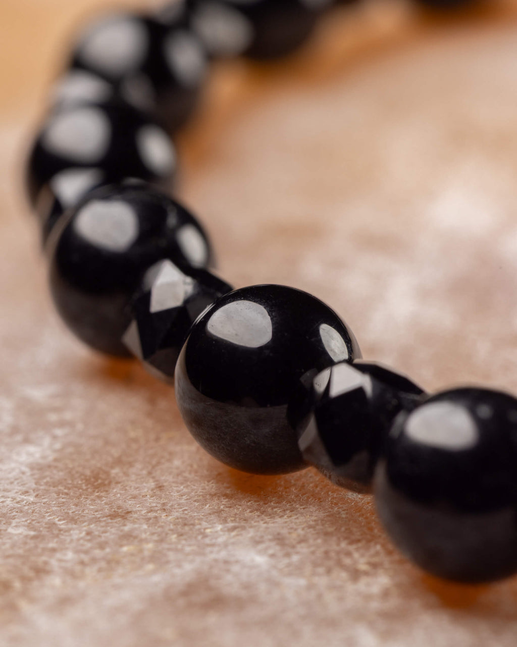 Cuentas de Espinela Negra y Turmalina Negra facetada en fila, círculo de la pulsera al fondo
