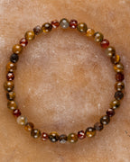 Pulsera Relámpago Creativo con Pietersita y Granate Espesartina, pieza completa en círculo sobre piedra