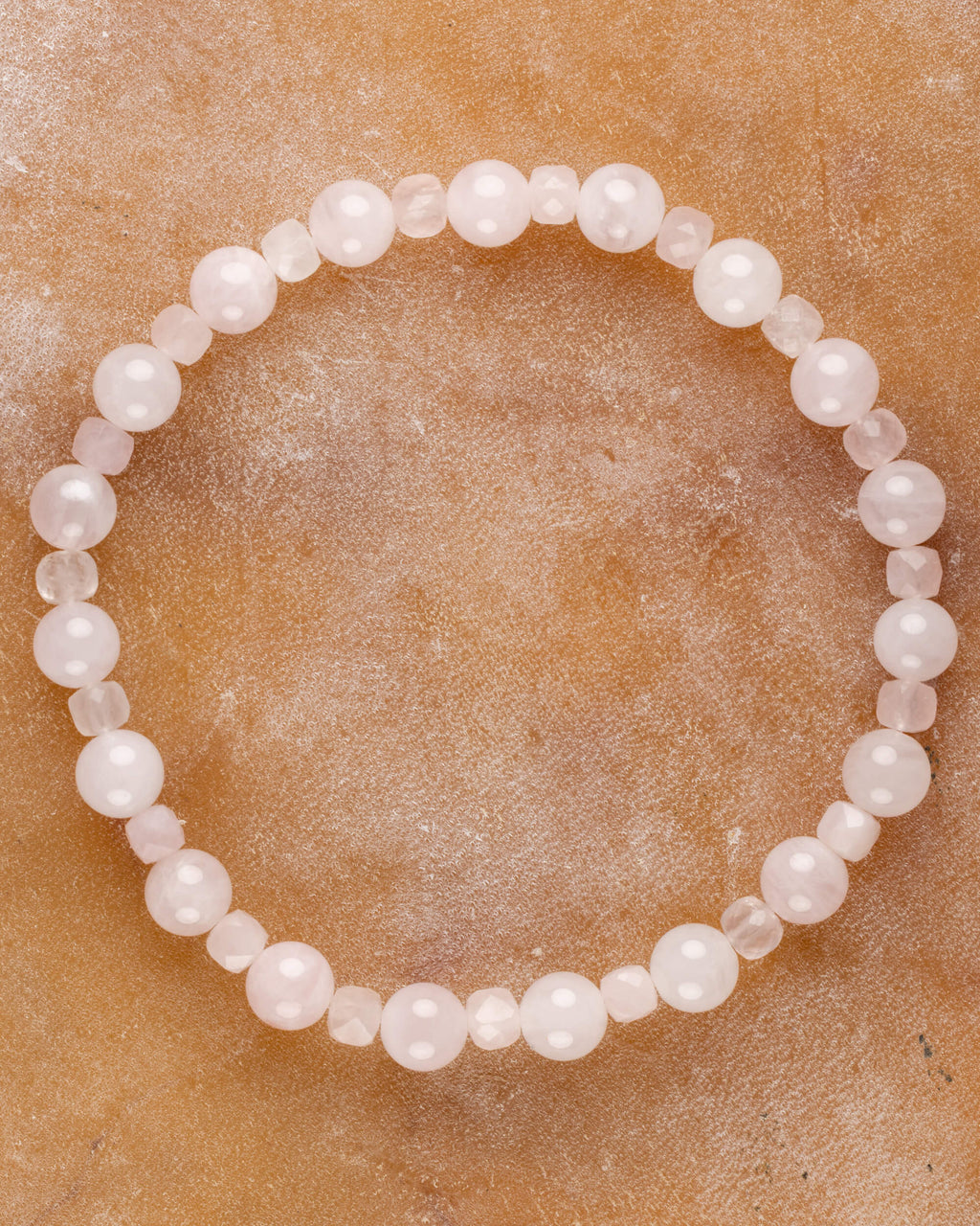 Pulsera de Cuarzo Rosa, pieza completa en círculo sobre superficie de mármol claro