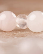 Detalle macro de una cuenta facetada de Cuarzo Rosa entre cuentas lisas