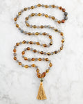 Japa Mala Trama del Alma con Pietersita, Ámbar y Labradorita, pieza completa en espiral sobre mármol