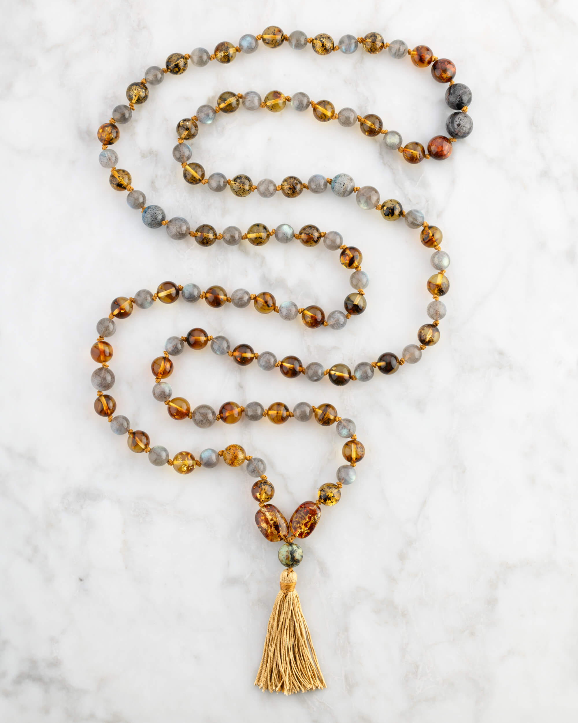 Japa Mala Trama del Alma con Pietersita, Ámbar y Labradorita, pieza completa en espiral sobre mármol