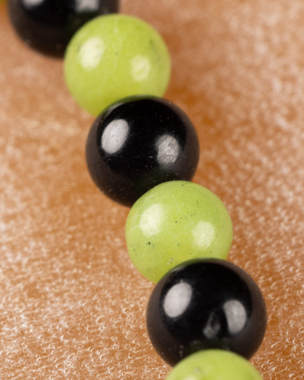 Detalle macro de las cuentas de Jade Verde y Turmalina Negra en fila