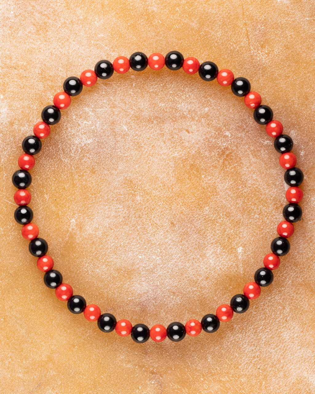 Pulsera de Coral Rojo y Turmalina Negra, pieza completa en círculo sobre superficie clara