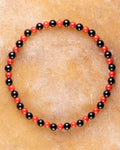 Pulsera de Coral Rojo y Turmalina Negra, pieza completa en círculo sobre superficie clara