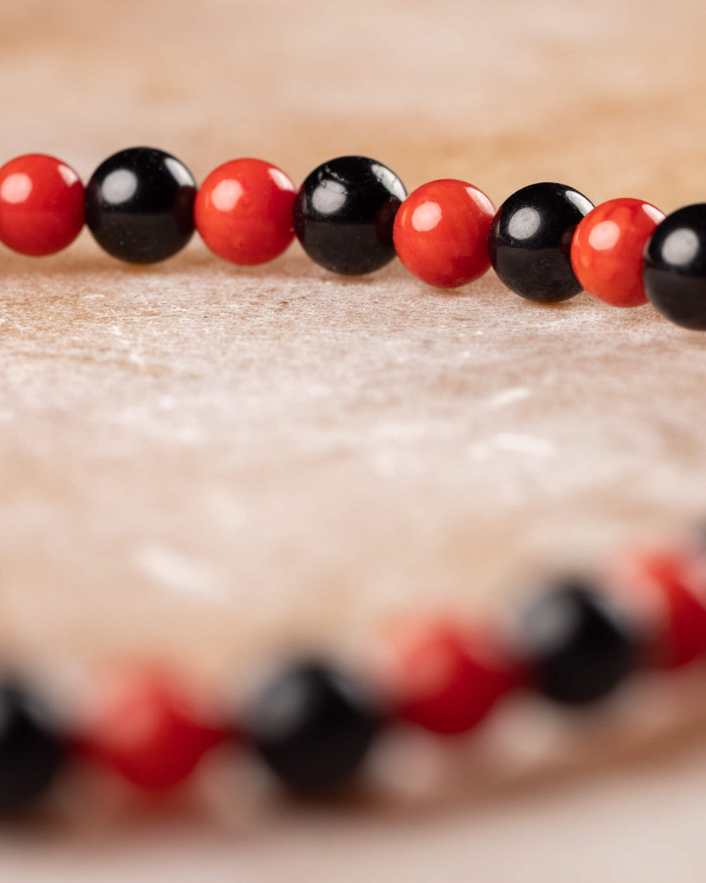 Pulsera de Coral Rojo y Turmalina Negra vista de perfil, cuentas en primer plano
