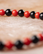 Pulsera de Coral Rojo y Turmalina Negra vista de perfil, cuentas en primer plano