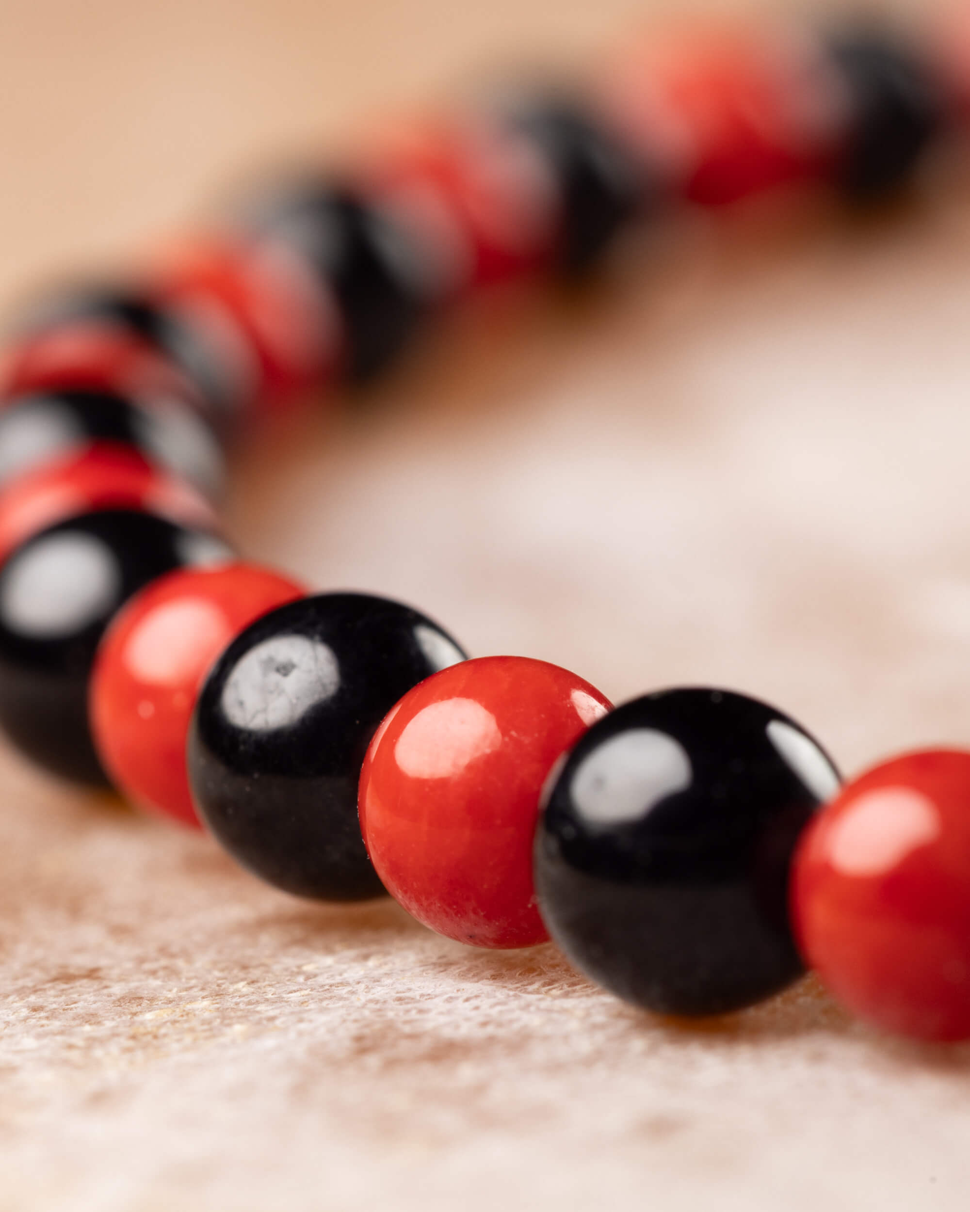 Pulsera de Coral Rojo y Turmalina Negra en curva, cuentas en primer plano