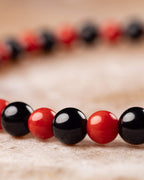 Pulsera de Coral Rojo y Turmalina Negra en ángulo cercano sobre superficie clara