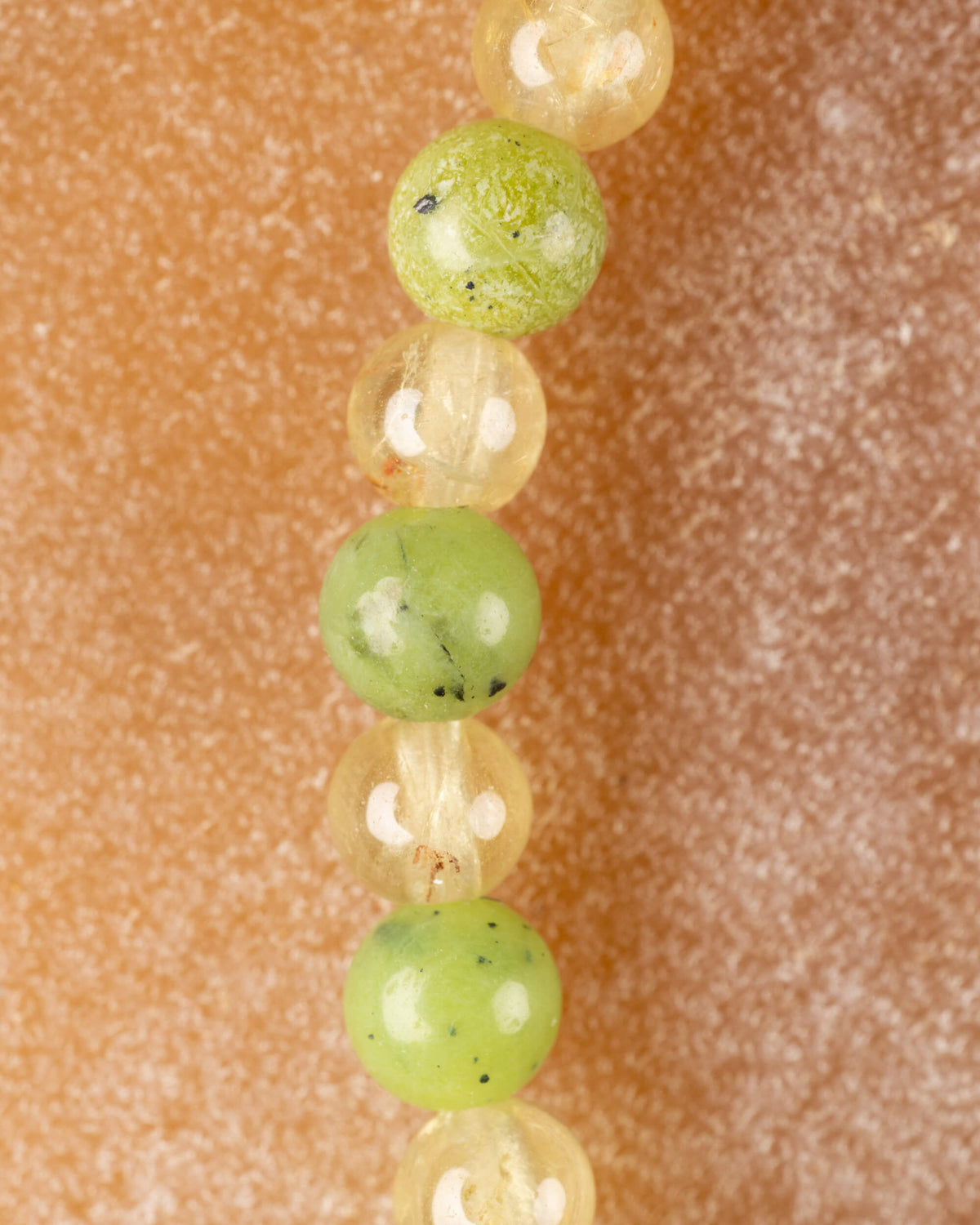 Detalle vertical de las cuentas de Jade Verde y Cuarzo Rutilado con fondo desenfocado