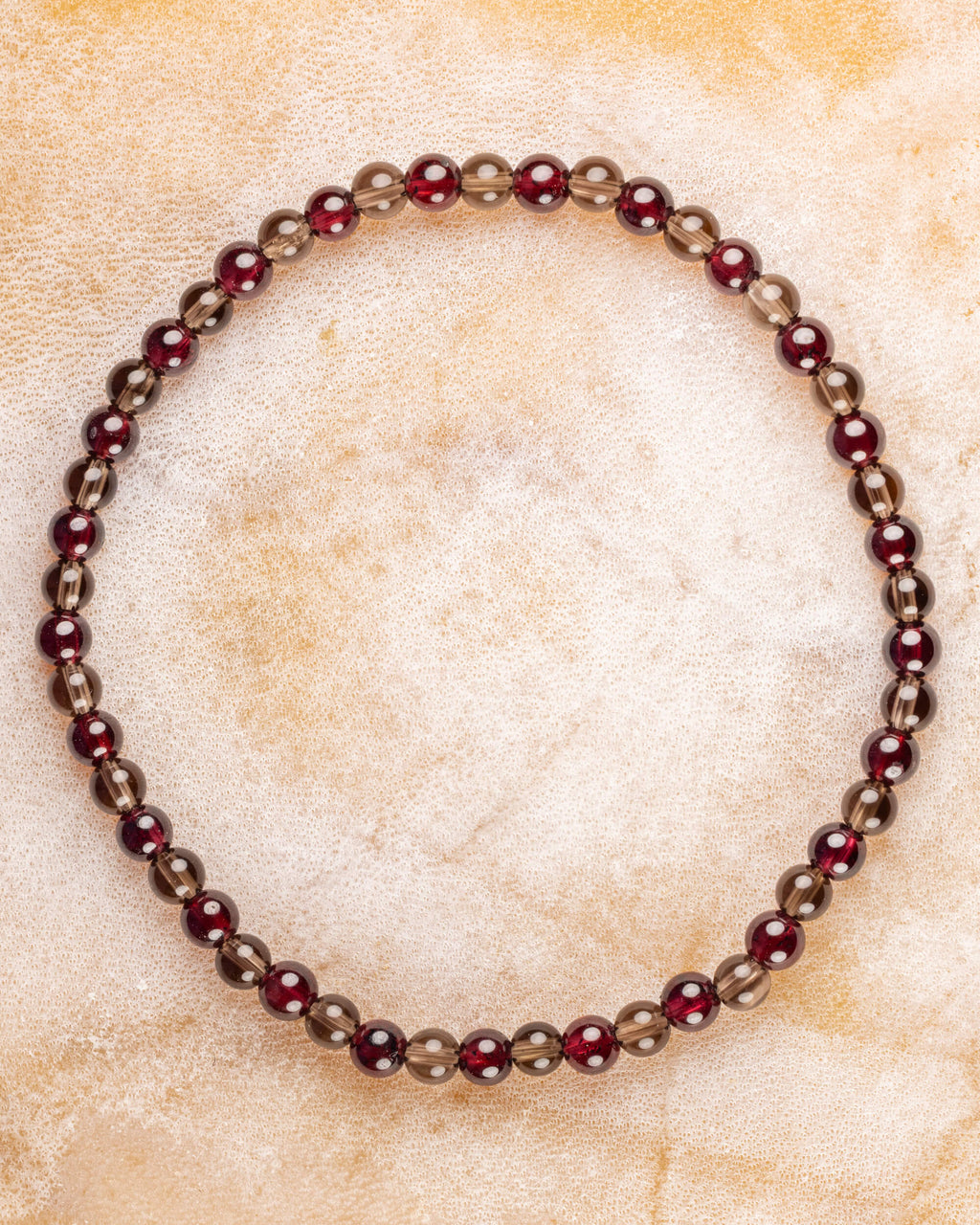 Pulsera de Granate Rojo y Cuarzo Ahumado, pieza completa sobre superficie clara