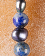 Detalle macro vertical de Perla Negra entre cuentas de Lapislázuli