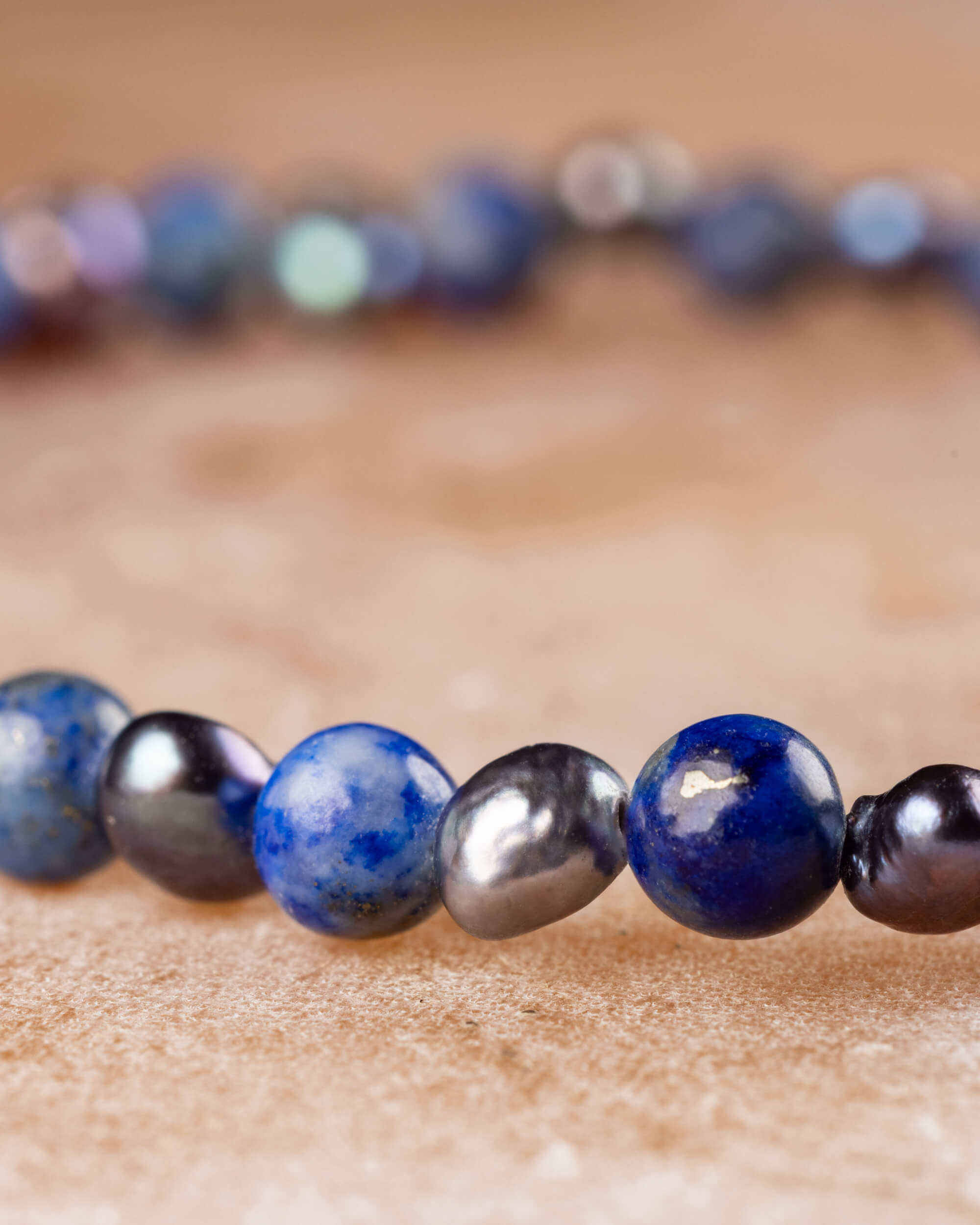 Pulsera de Lapislázuli y Perla Negra en perspectiva curva sobre superficie clara