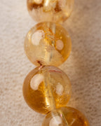 Detalle macro de cuentas de Citrino apiladas, tonos dorado y ambar oscuro