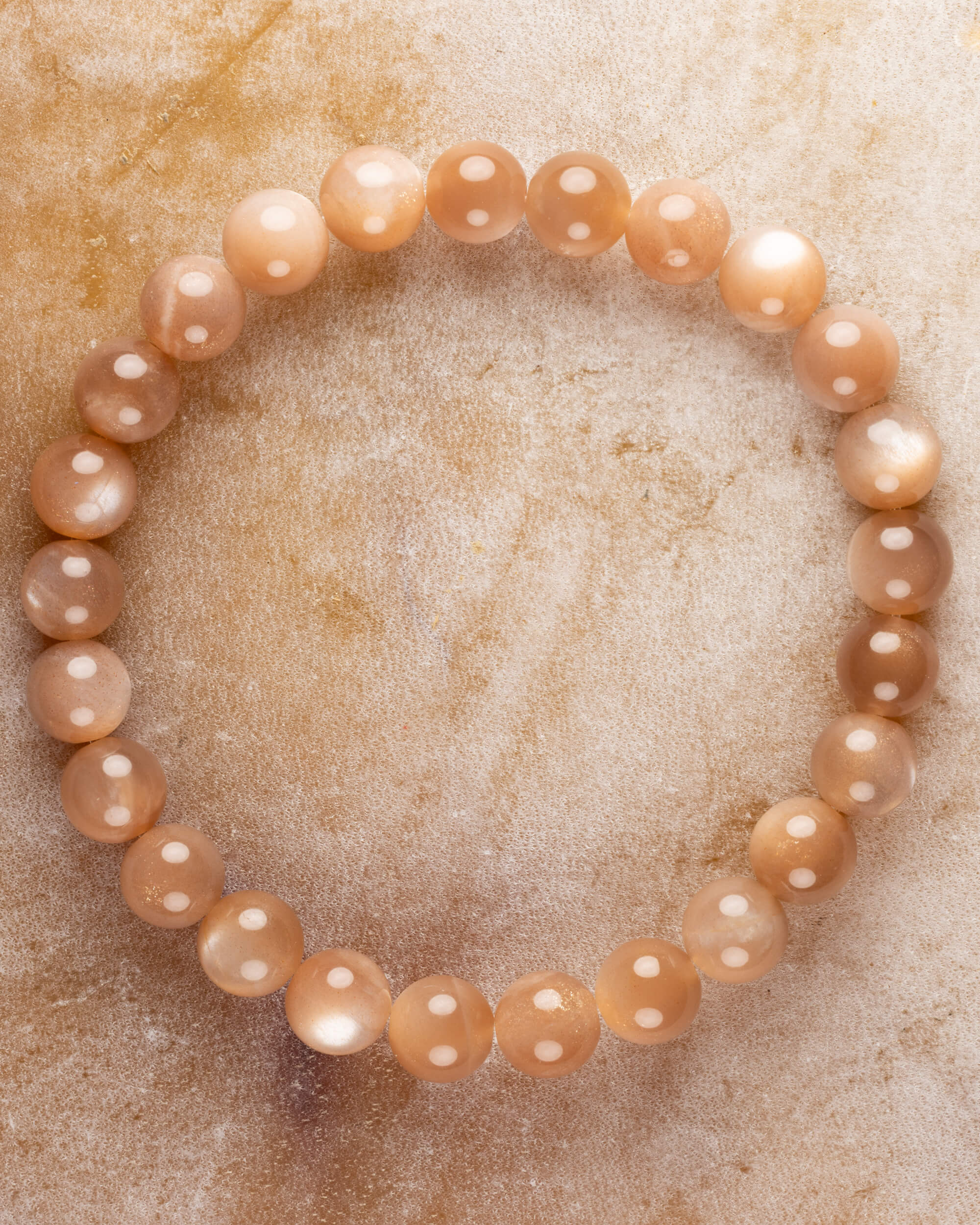 Pulsera de Piedra Sol Naranja de 8 mm, pieza completa en círculo sobre superficie dorada